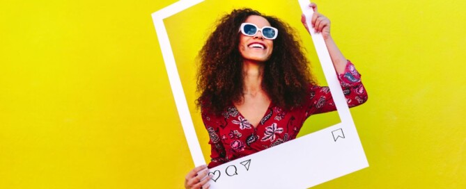 woman holding a polaroid frame against a yellow background