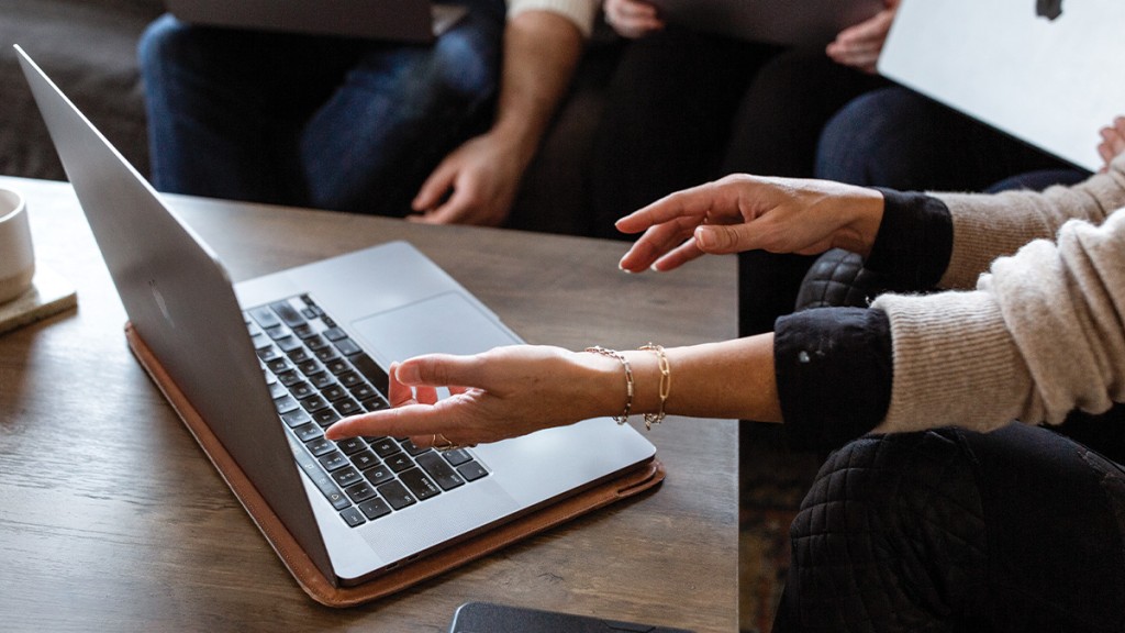 woman pointing to computer during a meeting with colleagues